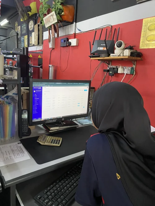 Kakitangan bengkel sedang menggunakan sistem pengurusan bengkel Engarage di komputer meja untuk semakan job order dan pengurusan pelanggan